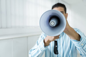 young businessman in office screaming on the megaphone